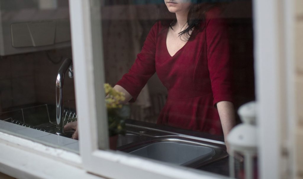 キッチンの窓辺に立つ女性